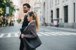 Man in a suit and woman in a plaid blazer crossing a city street